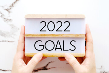 Hands holding 2022 goals wood box over marble background, banner, business new year, aim to success in business