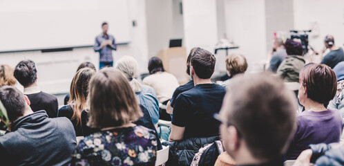 man giving presentation in lecture hall at university.