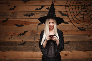 Halloween witch concept - Happy Halloween Sexy Witch holding posing over old wooden studio background.