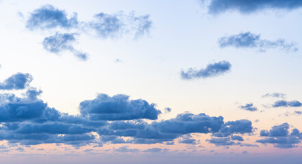 Wall Mural - Natural background, stunning view of some fluffy clouds on a purple sky during a beautiful sunrise. Sardinia, Italy.