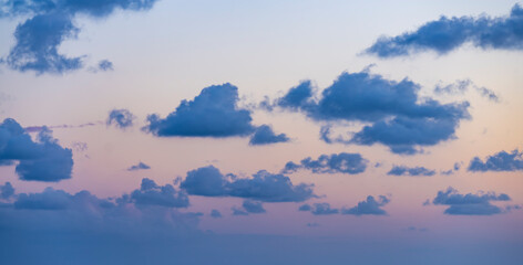 Wall Mural - Natural background, stunning view of some fluffy clouds on a purple sky during a beautiful sunrise. Sardinia, Italy.