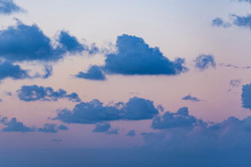 Wall Mural - Natural background, stunning view of some fluffy clouds on a purple sky during a beautiful sunrise. Sardinia, Italy.