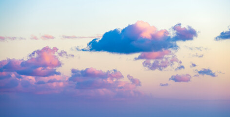 Wall Mural - Natural background, stunning view of some fluffy clouds on a purple sky during a beautiful sunrise. Sardinia, Italy.