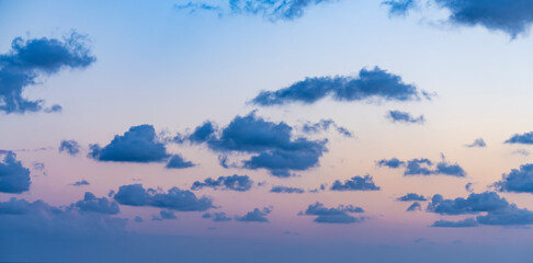 Wall Mural - Natural background, stunning view of some fluffy clouds on a purple sky during a beautiful sunrise. Sardinia, Italy.