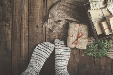 Wall Mural - Christmas, New Year composition with gift boxes, knitted blanket and women feet on wooden floor. Preparing for the winter holidays