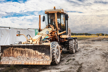 Road grader - heavy equipment for road construction and earthworks. Leveling and improvement of the ground surface. Construction of roads and transport communications.