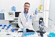 © Krakenimages.com - Middle age man working at scientist laboratory smiling with happy face looking and pointing to the side with thumb up.