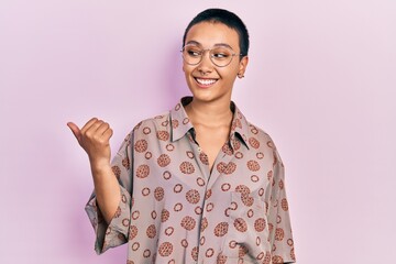 Sticker - Beautiful hispanic woman with short hair wearing glasses smiling with happy face looking and pointing to the side with thumb up.