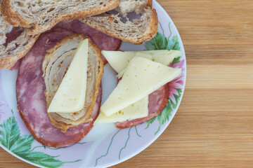 Wall Mural - two slices of sausage in a plate with a piece of meatloaf, cheese and bread