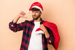 Young arab man disguised as santa claus isolated on beige background feels proud and self confident, example to follow.