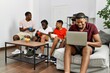 © Krakenimages.com - Group of african american people sitting on the sofa at home. Man smiling happy using laptop.