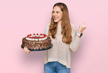 Sticker - Young blonde woman celebrating birthday holding big chocolate cake screaming proud, celebrating victory and success very excited with raised arms