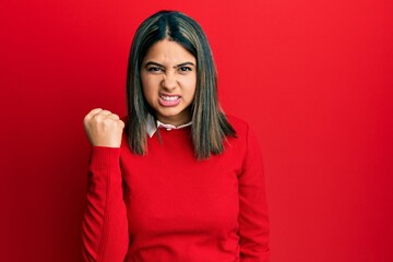 Poster - Young latin woman wearing casual clothes angry and mad raising fist frustrated and furious while shouting with anger. rage and aggressive concept.