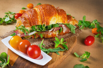 Wall Mural - Croissant sandwich with prosciutto and cherry tomatoes on wooden chopping board