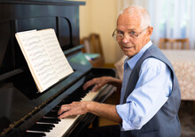 Man Practicing Playing Piano In The Living Room Of His Home After Retirement From Work