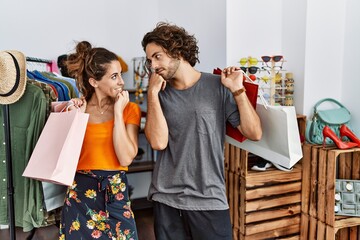 Wall Mural - Young hispanic couple holding shopping bags at retail shop with hand on chin thinking about question, pensive expression. smiling with thoughtful face. doubt concept.