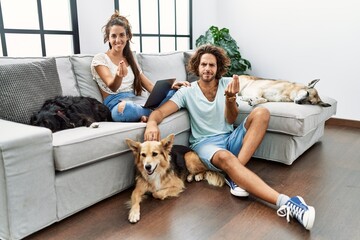 Sticker - Young hispanic couple with dogs relaxing at home doing italian gesture with hand and fingers confident expression