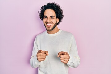 Sticker - Handsome hispanic man wearing casual white sweater pointing fingers to camera with happy and funny face. good energy and vibes.