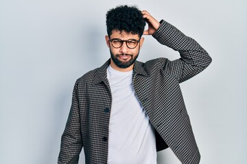 Sticker - Young arab man with beard wearing glasses confuse and wonder about question. uncertain with doubt, thinking with hand on head. pensive concept.