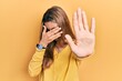 © Krakenimages.com - Beautiful hispanic woman wearing casual yellow sweater covering eyes with hands and doing stop gesture with sad and fear expression. embarrassed and negative concept.