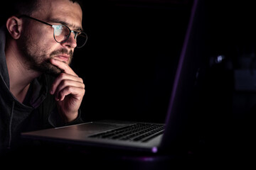 Wall Mural - A man with glasses works at a computer late at night.