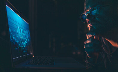 A man analyzing stock market charts, financial data on an electronic board.