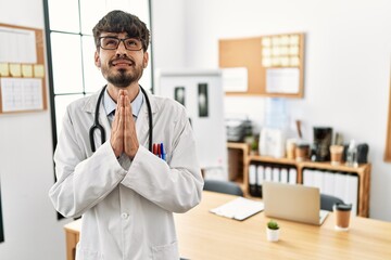 Sticker - Hispanic man with beard wearing doctor uniform and stethoscope at the office begging and praying with hands together with hope expression on face very emotional and worried. begging.