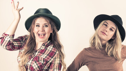 Two fashionable females wearing hat