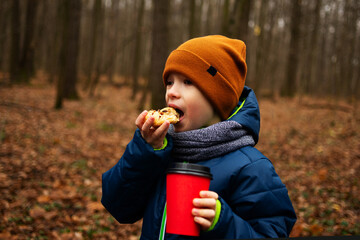 Lifestyle portrait boy in autumn park have a snack