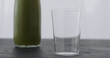 green matcha drink in glass bottle on black oak table with copy space