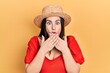 © Krakenimages.com - Young hispanic woman wearing summer hat shocked covering mouth with hands for mistake. secret concept.