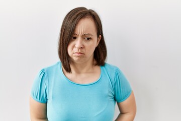 Wall Mural - Young down syndrome woman standing over isolated background with hand on stomach because indigestion, painful illness feeling unwell. ache concept.