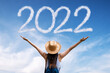 Brunette woman greets the 2022 against clouds