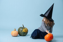 Witch Girl Is Playing With Pumpkins, Sitting On The Floor.