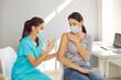 © Studio Romantic - Highly qualified nurse gives Covid-19 vaccine to responsible female patient at modern medical center. Beautiful young woman wearing mouth covering getting flu shot during seasonal vaccination campaign