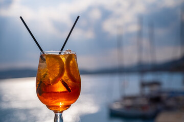 Wall Mural - Orange drink or cocktail standing at the little table at the restaurant or cafe with sea background