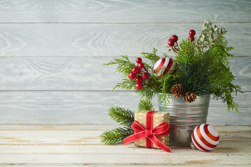 Wall Mural - Christmas pine tree branches in bucket with gift box and decorations on wooden table background