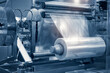 © Aleksandr Matveev - The operation of automatic plastic bag production machine with lighting effect. Close-up of the roller of the plastic bag production machine in the light blue scene.