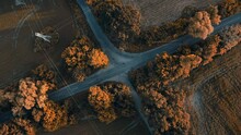 Countrysise Road Top Down. Autumn Orange Trees Aerial View. Country Rural Crossroad At Sunset. Agriculture Farm Fields And Electric Poles Around. Low Traffic Transportation. Delivery Concept. Zoom Out