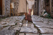 © kasto - Detail shot of female legs wearing comfortable travel sandals walking on old medieval cobblestones street dring sightseeing city tour. Travel, tourism and adventure concept