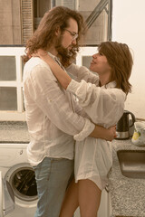 Young attractive couple in love hugging in the kitchen while they are doing the dishes.