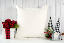 Throw Pillow Cushion Product Mockup. Christmas Farmhouse Theme SVG Craft Product Mockup Styled With Gift With Buffalo Plaid Bow And Farmhouse Style Gnomes Against A White Wood Background.