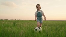 Little Kid Plays Football At Sunset, Baby Runs Around Green Football Field And Kicks Ball, Child Runs To Floor In Meadow And Smiles, Learns How To Kick Ball, Dream Of Becoming Team Footballer