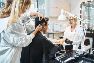 Woman manicurist grinding down client nails during haircut