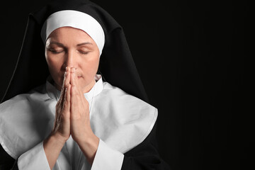 Wall Mural - Mature nun praying on dark background