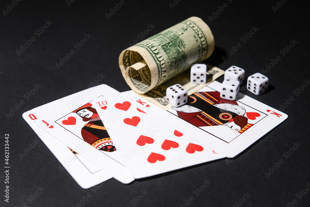 Poker chips, dices, dollar banknotes and playing cards on dark background