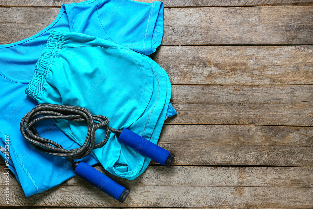 Sportswear and skipping rope on wooden background