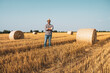 © djoronimo - Happy farmer is standing beside bales of hay. He is satisfied because of successful harvesting.