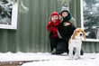 Adorable couple posing for a photo with their beagle outdoors at winter