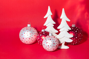 Wall Mural - Christmas card with snow-covered white New Year trees and colorful balls on bright red background.